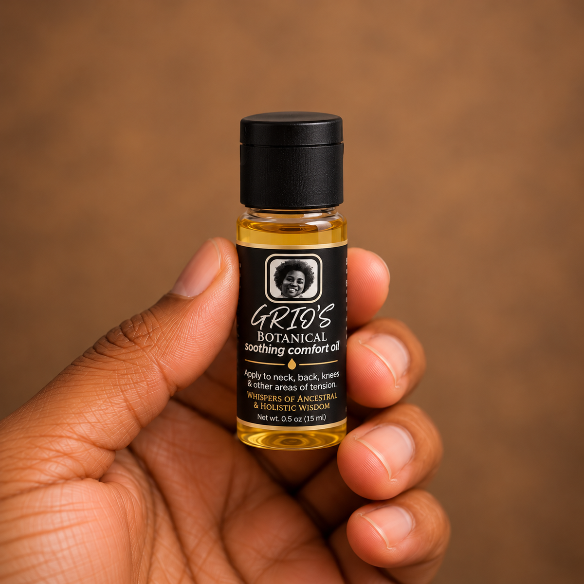 Close-up of a hand holding a 0.5 oz sample bottle of GRIO’S Botanical Soothing Comfort Oil, featuring a clear amber bottle, black cap and signature black-and-gold label against a warm brown background.